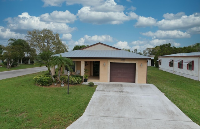 view of front of house with driveway, metal roof, a garage, and a front lawn