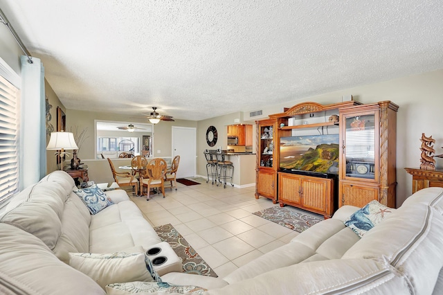 living room featuring light tile patterned floors, ceiling fan, a textured ceiling, and visible vents