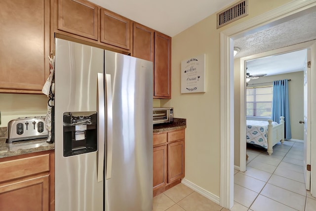 2050 Oleander Blvd Unit 1106, Fort Pierce, FL 34950 - kitchen with stainless steel fridge with ice dispenser, light tile patterned floors, brown cabinetry, dark stone countertops, and baseboards