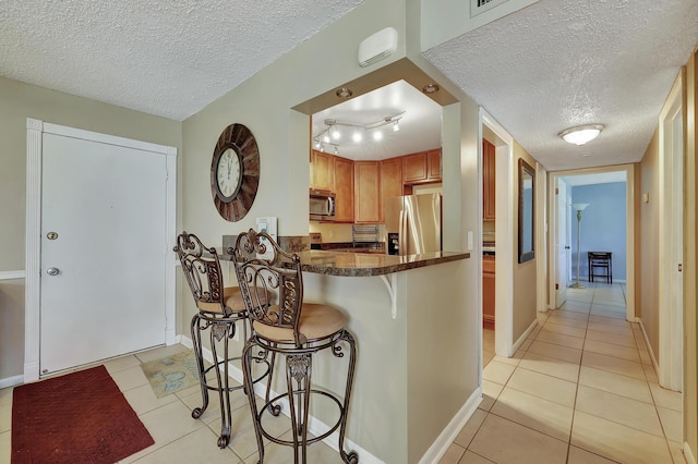 2050 Oleander Blvd Unit 1106, Fort Pierce, FL 34950 - kitchen featuring appliances with stainless steel finishes, a textured ceiling, light tile patterned flooring, a breakfast bar, and baseboards