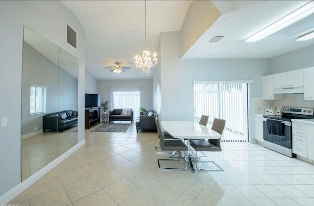 tiled dining space featuring ceiling fan with notable chandelier and high vaulted ceiling