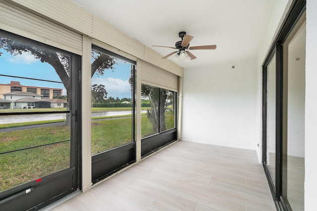 unfurnished sunroom featuring a water view and ceiling fan