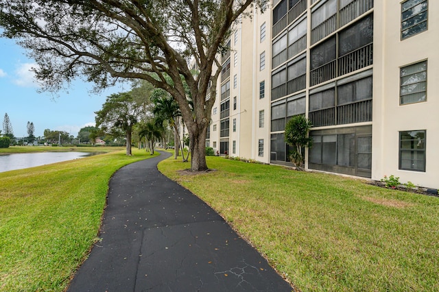 surrounding community with a water view and a lawn