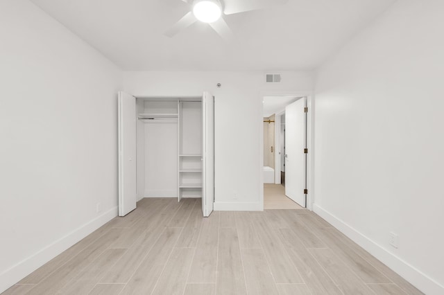 unfurnished bedroom featuring ceiling fan, light wood-type flooring, ensuite bath, and a closet