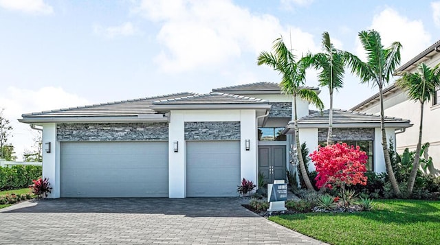 view of front of property with a tiled roof, decorative driveway, an attached garage, and stucco siding