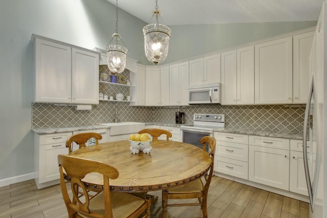 kitchen with white cabinetry, sink, white appliances, light stone counters, and pendant lighting