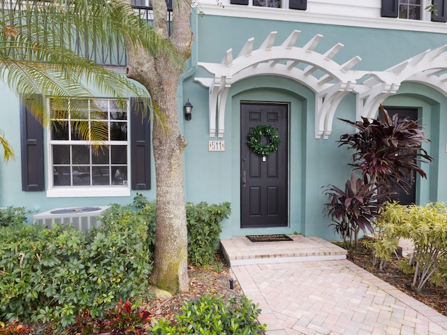 entrance to property featuring central AC and stucco siding