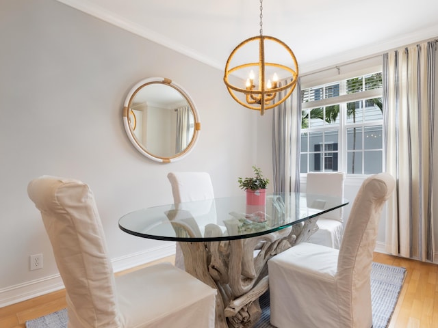 dining space with ornamental molding, a notable chandelier, light wood-style flooring, and baseboards