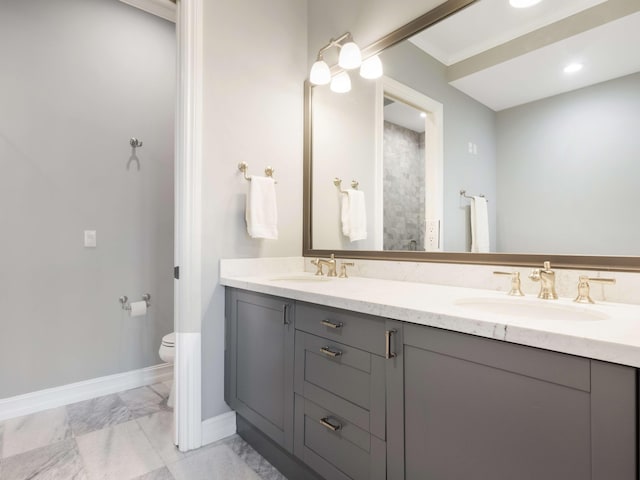 bathroom featuring baseboards, a sink, toilet, and double vanity