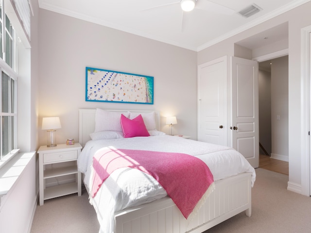 carpeted bedroom featuring baseboards, visible vents, ceiling fan, and ornamental molding