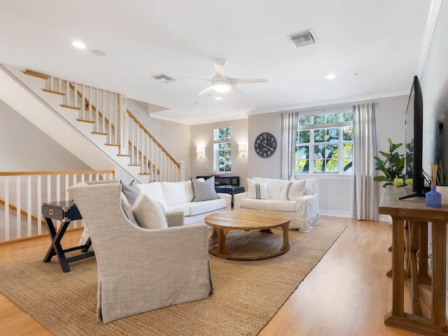 living room featuring light wood-style floors, stairway, visible vents, and crown molding