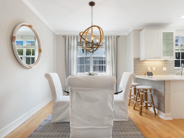 dining area with ornamental molding, light wood-type flooring, and baseboards