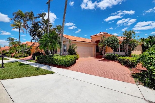 mediterranean / spanish home with a garage, decorative driveway, a tile roof, and stucco siding