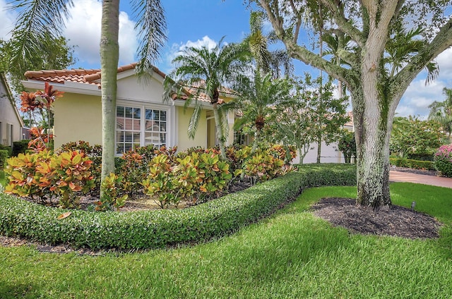 view of property exterior with a tiled roof, a lawn, and stucco siding