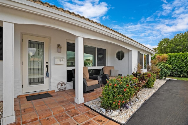 entrance to property with a patio area, brick siding, and a tiled roof