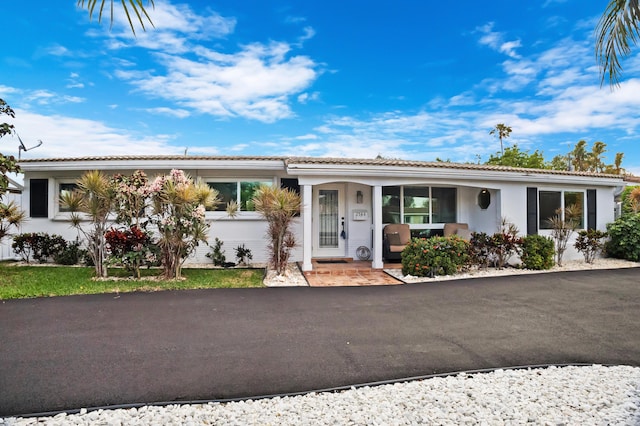 ranch-style house featuring a tile roof and stucco siding