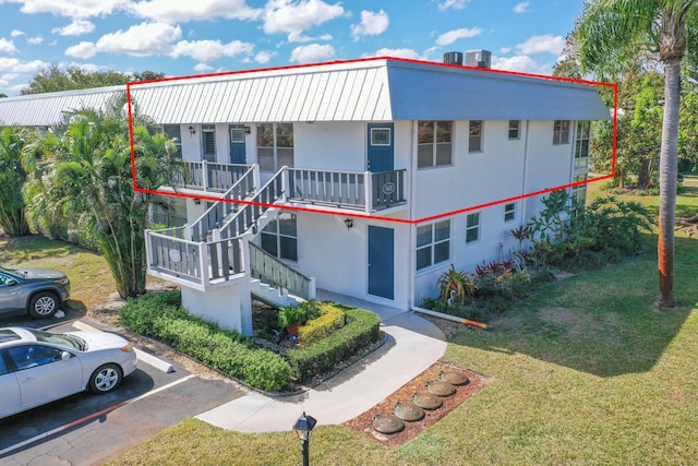 view of front of house featuring a front yard, stairway, uncovered parking, a porch, and stucco siding