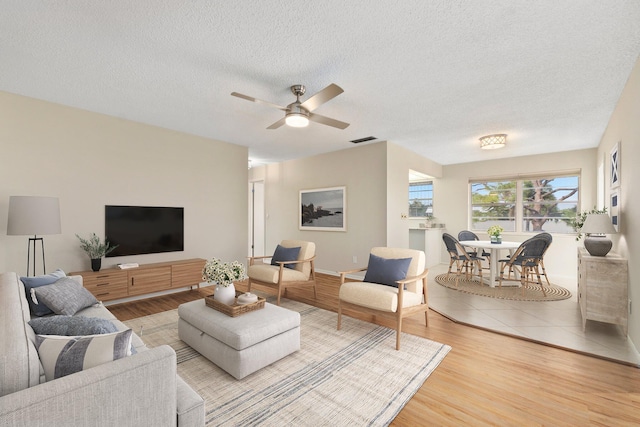 living room with visible vents, ceiling fan, a textured ceiling, and wood finished floors