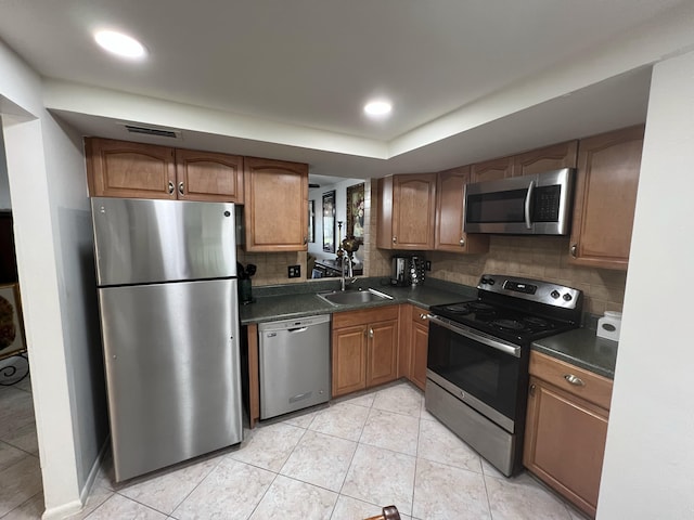 kitchen featuring appliances with stainless steel finishes, light tile patterned flooring, sink, and tasteful backsplash