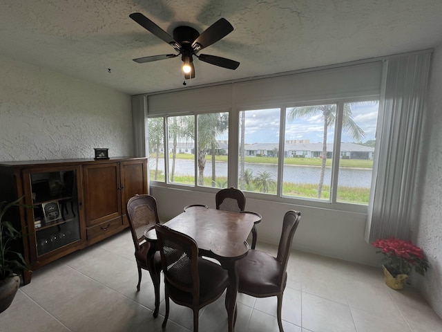 dining space with a water view, plenty of natural light, and a textured ceiling