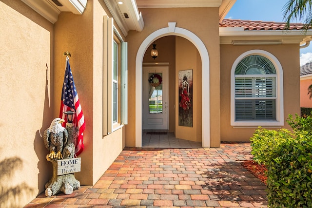 doorway to property featuring a tile roof and stucco siding