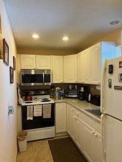 kitchen with light countertops, white appliances, white cabinets, and recessed lighting