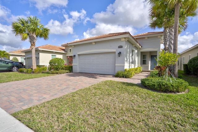 mediterranean / spanish-style house with an attached garage, stucco siding, a front lawn, a tile roof, and decorative driveway