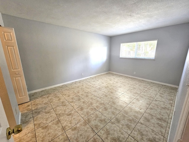 spare room with a textured ceiling and baseboards