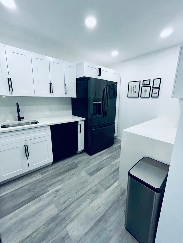 kitchen featuring a sink, black appliances, light countertops, and white cabinets