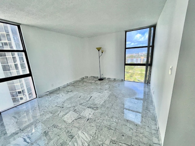 spare room with marble finish floor, floor to ceiling windows, and a textured ceiling
