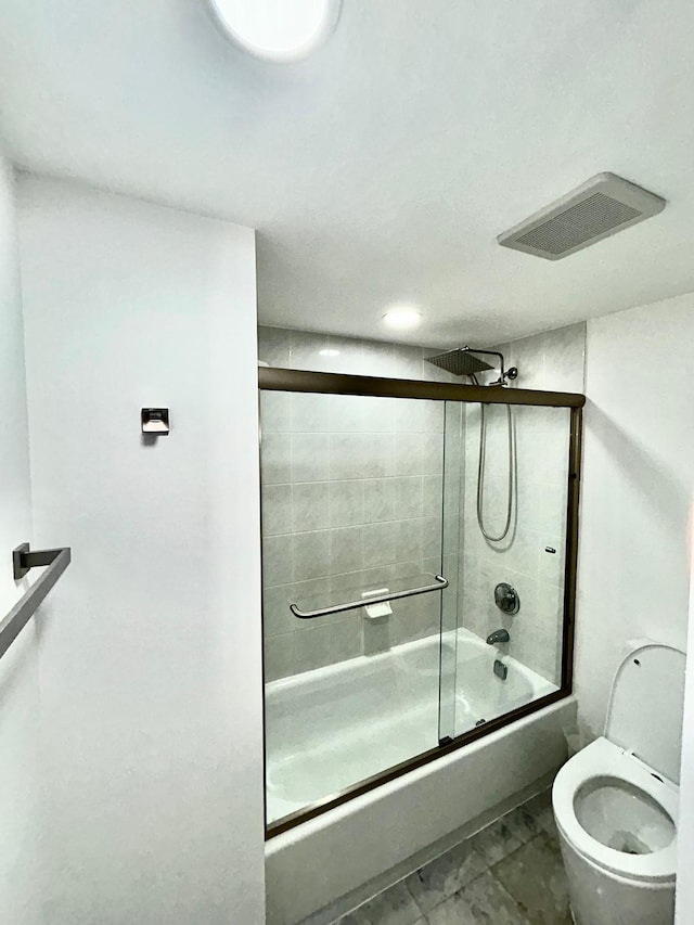 bathroom with toilet, visible vents, and combined bath / shower with glass door
