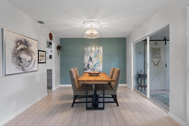 10137 S 42nd Ave S, Boynton Beach, FL 33436 - dining room featuring a textured ceiling, baseboards, visible vents, an accent wall, and light wood-style floors