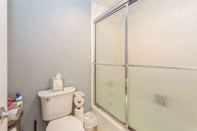 bathroom with combined bath / shower with glass door and toilet