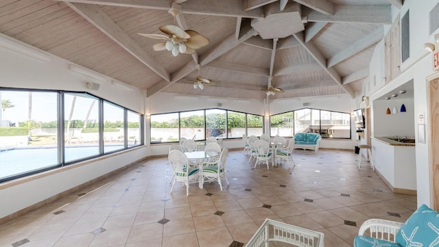 unfurnished sunroom featuring ceiling fan, plenty of natural light, vaulted ceiling with beams, and wooden ceiling