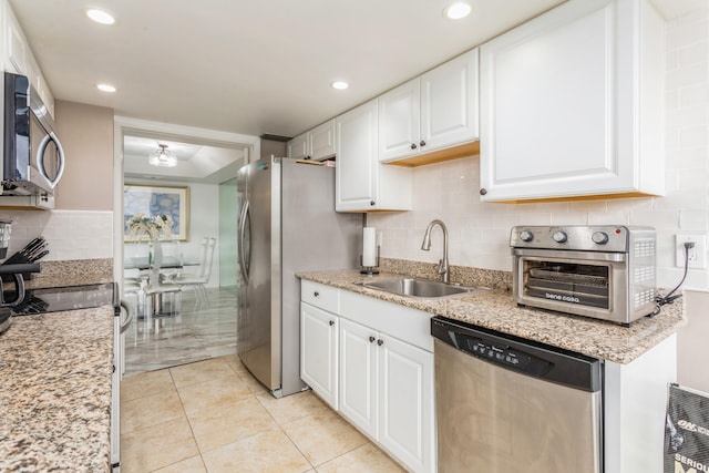 kitchen featuring sink, backsplash, appliances with stainless steel finishes, white cabinets, and light tile patterned flooring