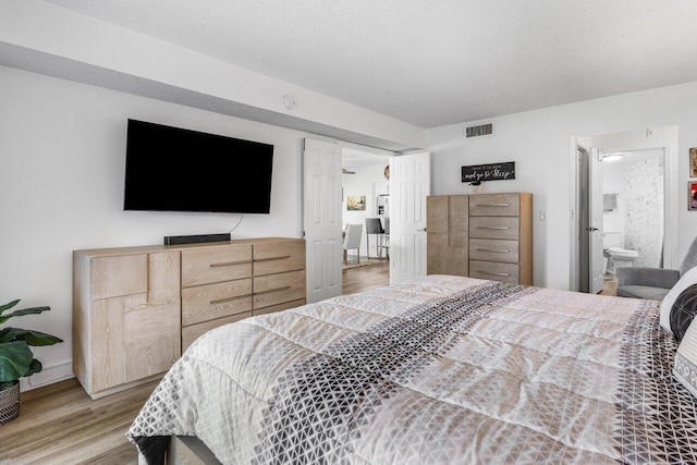 bedroom with a textured ceiling, visible vents, and wood finished floors