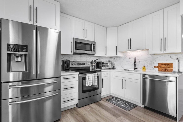 kitchen featuring light countertops, appliances with stainless steel finishes, a sink, and white cabinets