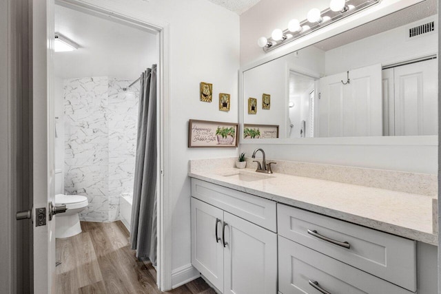 full bath with toilet, wood finished floors, visible vents, vanity, and shower / bathtub combination with curtain