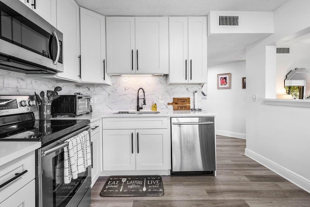 kitchen featuring appliances with stainless steel finishes, a sink, visible vents, and white cabinetry