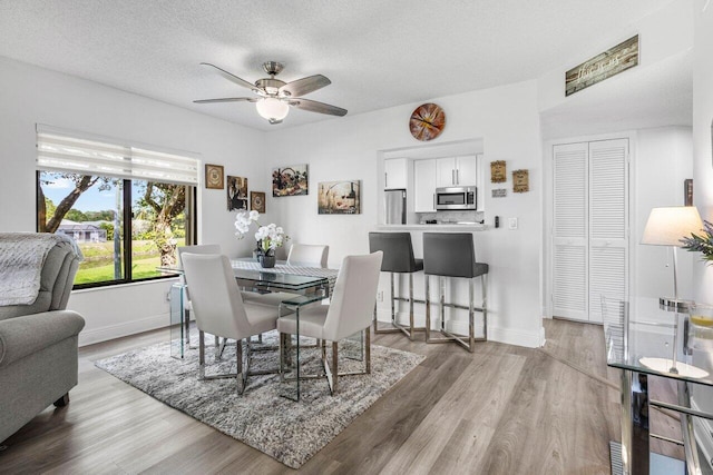 dining space featuring a textured ceiling, baseboards, and wood finished floors