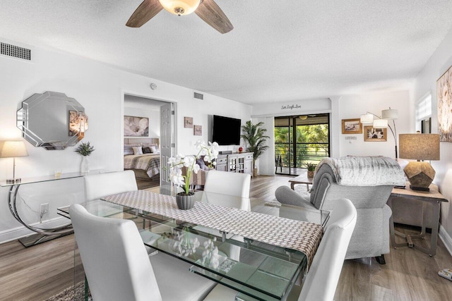 dining room featuring a textured ceiling, ceiling fan, wood finished floors, and visible vents