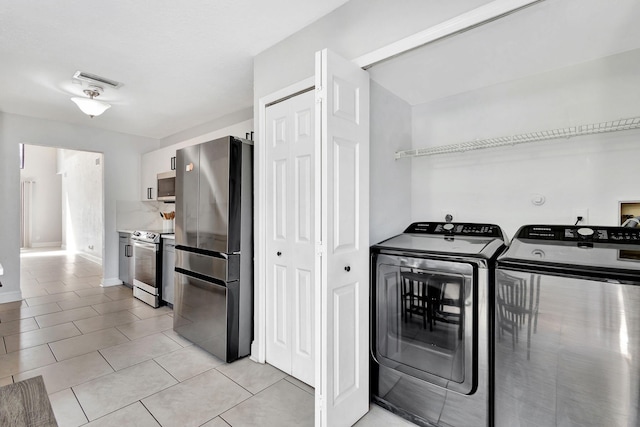 laundry area with light tile patterned floors, laundry area, independent washer and dryer, and visible vents