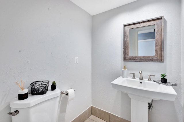 bathroom featuring a textured wall, tile patterned flooring, toilet, and baseboards