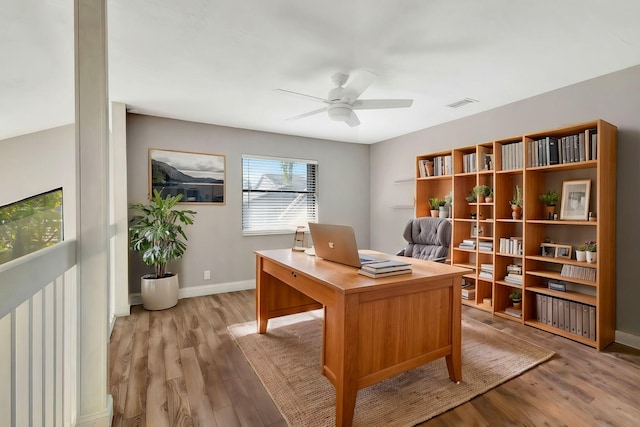 office with light wood-style floors, baseboards, visible vents, and a ceiling fan