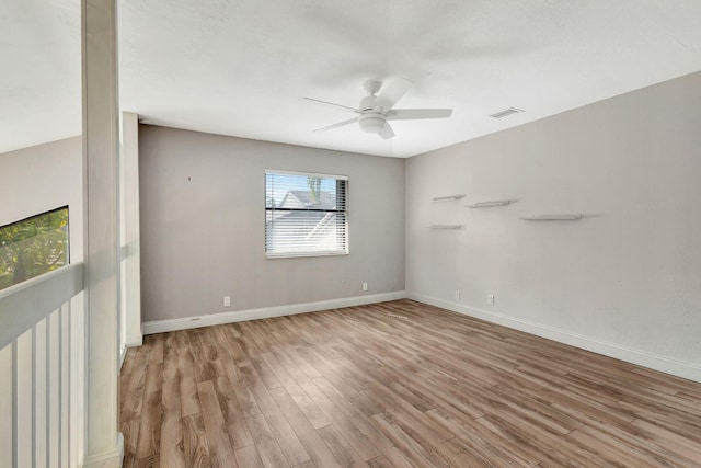 empty room featuring light wood finished floors, baseboards, visible vents, and ceiling fan