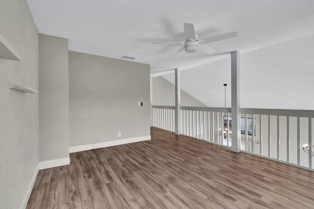 spare room with visible vents, vaulted ceiling, wood finished floors, baseboards, and ceiling fan with notable chandelier