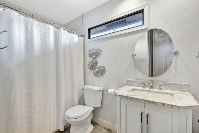 bathroom with toilet, a textured wall, vanity, and baseboards