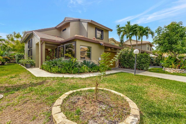 view of front of house with a front yard, concrete driveway, and stucco siding