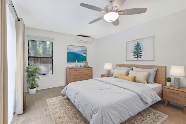 bedroom with a wall unit AC, light tile patterned floors, baseboards, and a ceiling fan