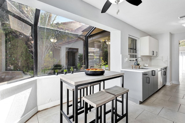 kitchen with light tile patterned flooring, a sink, white cabinetry, light countertops, and decorative backsplash